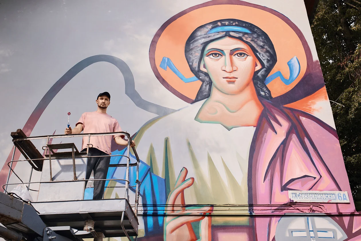 Резидент Православной арт-резиденции в 2024 году Саша Цыпко в на фоне своего мурала «Архангел» в Нижнем Новгороде