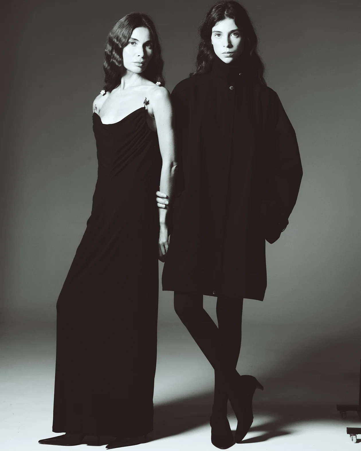 На Оксане: платье, BOTTEGA VENETA, туфли, SAINT LAURENT, все ЦУМ.На Варваре: плащ, TOTEME, туфли, NEOUS, все ЦУМ; колготки, CALZEDONIA